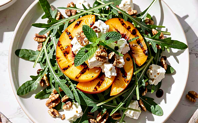 Arugula salad with grilled peaches, goat cheese, and toasted nuts