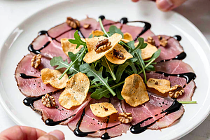 Beef Tenderloin Carpaccio with Arugula, Oscypek Chips, and Black Cumin Sauce