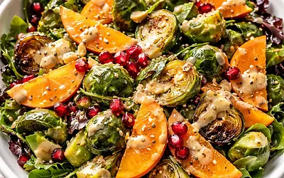 Fusion salad with roasted Brussels sprouts, persimmon, and pomegranate with miso-tahini dressing