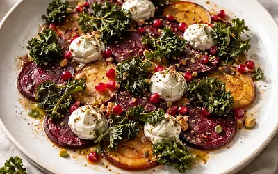 Elegant roasted beet carpaccio with goat cheese cream, kale chips, and pomegranate