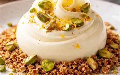 White chocolate mousse with a hint of orange on an oat-almond crumble with roasted pistachios