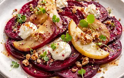Layered beetroot carpaccio with marinated pear, goat cheese cream, and nut crumble