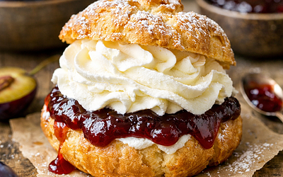 Street cream puff with cream and plum jam